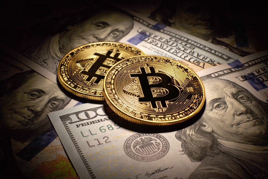 bitcoin money dollar - Digital Wager Wire Two gold Bitcoin coins rest on scattered U.S. hundred-dollar bills, illustrating crypto vs cash.