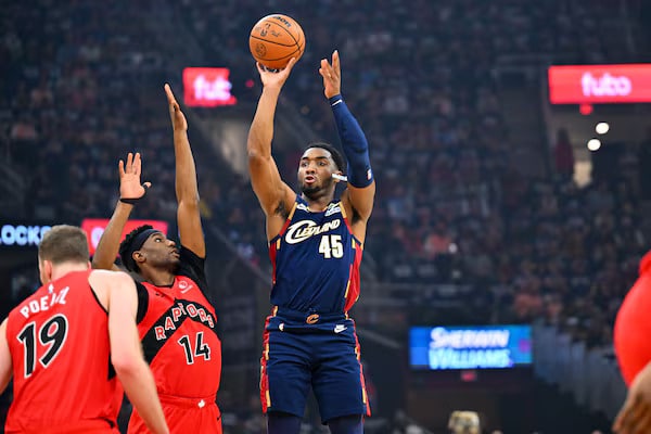 cavs win - Digital Wager Wire Basketball player in a blue uniform (number 45) shoots over two red-jersey defenders during a game in a crowded arena.