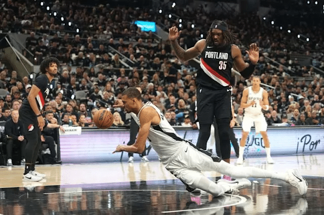 knock down - Digital Wager Wire Basketball player in white dives for the loose ball as a Portland Trail Blazers defender (number 35) watches in a crowded arena.