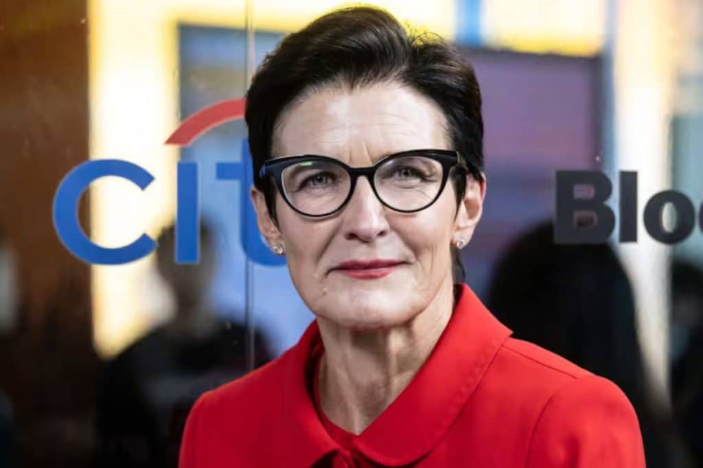 citi group ceo 1 - Digital Wager Wire Professional portrait of a woman with short dark hair and black glasses, wearing a red blazer in front of a glass wall with a Citi sign.