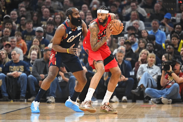 harden - Digital Wager Wire Toronto Raptors player in red uniform dribbles past a Cleveland Cavaliers defender during a game, with a crowded arena watching intently.