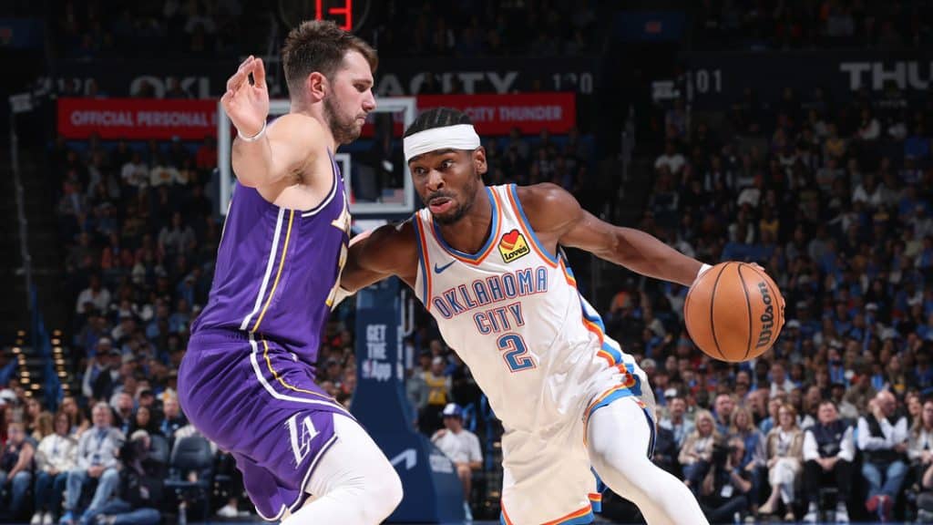 luca 1 - Digital Wager Wire Oklahoma City Thunder guard dribbles past a Los Angeles Lakers defender in a crowded basketball game.