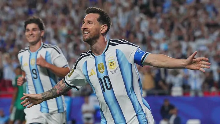 happy messi - Digital Wager Wire Argentine soccer player wearing number 10 jersey with captain's armband celebrating with arms spread, on a crowded stadium crowd behind him