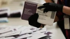 mail ballot - Digital Wager Wire Hands in black gloves holding a ballot return envelope during an election process in a polling setting