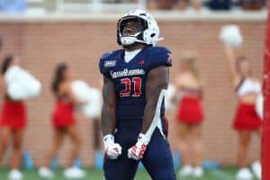 South Alabama football player, number 21, in navy uniform and helmet, celebrating with arms flexed on the field.
